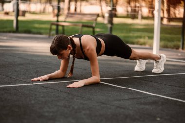 Genç bir bayan antrenör fitness sıkıştırma egzersizi yapıyor. Kız dışarıda antrenman yapıyor. Sağlıklı bir yaşam tarzı. Yüksek kalite fotoğraf