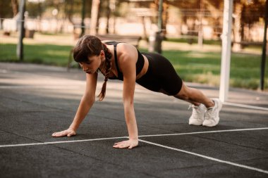 Genç bir bayan antrenör fitness sıkıştırma egzersizi yapıyor. Kız dışarıda antrenman yapıyor. Sağlıklı bir yaşam tarzı. Yüksek kalite fotoğraf