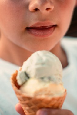 Waffle bardağında dondurma yiyen bir çocuğun yakın çekim görüntüsü. Makro. Dondurmadaki bir dilin detaylı görüntüsü, yaz zamanı, mutlu bir çocukluk. Yüksek kalite fotoğraf