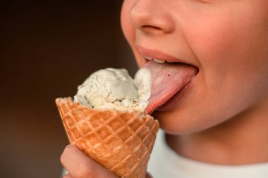 Waffle bardağında dondurma yiyen bir çocuğun yakın çekim görüntüsü. Makro. Dondurmadaki bir dilin detaylı görüntüsü, yaz zamanı, mutlu bir çocukluk. Yüksek kalite fotoğraf