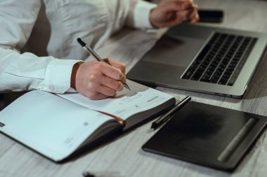 Bilgisayarın başında çalışan bir kız. Elinde telefon ve not defteri var. Çevrimiçi öğrenme, finans, iş, uzaktan çalışma. Çalışıyorum. Yüksek kalite fotoğraf