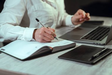 Bilgisayarın başında çalışan bir kız. Elinde telefon ve not defteri var. Çevrimiçi öğrenme, finans, iş, uzaktan çalışma. Çalışıyorum. Yüksek kalite fotoğraf