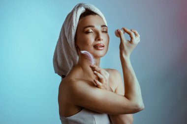 Guasha fırçasıyla yüzüne masaj yapan genç bir kadın. Yüz bakımı. Sağlıklı, parlayan bir ten. Yüksek kalite fotoğraf