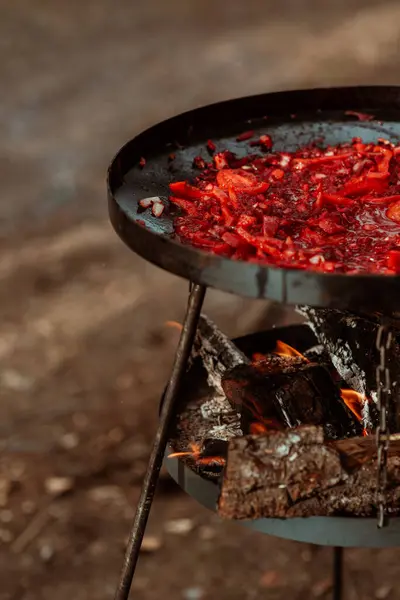 木の開いた火の上にグリル鍋で調理された野菜の垂直 屋外で調理する 大企業のための食事 高品質の写真 ロイヤリティフリーのストック写真