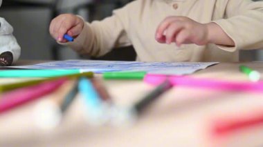 Yaratıcı çocuk evde pastel boyalarla resim çiziyor. Parlak, çocuk dostu bir çevreye odaklanmış ve meşgul..