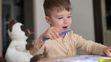 Yaratıcı çocuk evde pastel boyalarla resim çiziyor. Parlak, çocuk dostu bir çevreye odaklanmış ve meşgul..