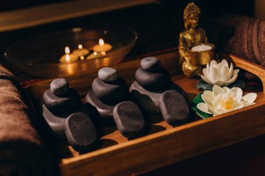 Nilüfer çiçekleri, taşlar, yağlar ve havlularla Tayland masaj setinin üst görüntüsü sakin bir spa atmosferi yaratıyor..