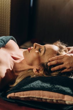 Kaplıca masasına uzanmış bir kadının geleneksel Tayland yüz masajı yaptırdığı bir fotoğraf. Yüksek kalite fotoğraf