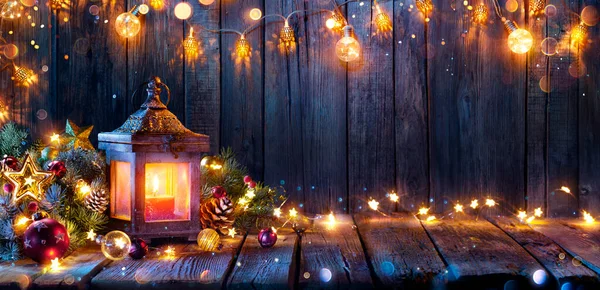 装飾とストリングライトで木製のテーブルに輝くクリスマスランタン ボケと背景に輝く効果 — ストック写真