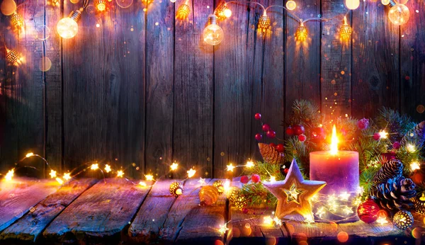 アドベント 装飾が施された木製のテーブルの上にクリスマスライトに輝くキャンドル 背景に隠されたボケときらびやかな効果 — ストック写真