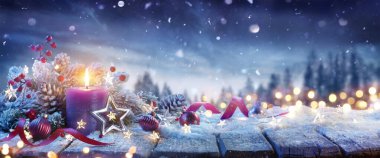 Advent Candle With Christmas Decoration On Snow Table And Abstract Defocused Landscape clipart