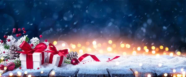 冬季蓝色背景下雪地礼品盒 雪夜圣诞礼物及红色装饰带着抽象的防盗灯 — 图库照片