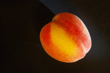 SONY DSC Ağız sulandıran sarı-kırmızı şeftali siyah bir arkaplan karşı, bir meyve gibi tat tomurcukları zevk, yapay ışık altında bir stüdyo ortamında fotoğraflandı.