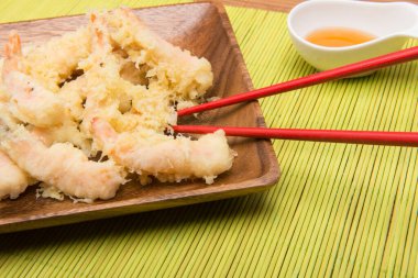 Bambu masa örtüsü üzerinde çubuklarla tempura karidesleri.