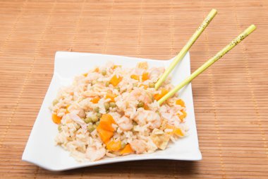 Bambu masa örtüsü üzerinde yemek çubukları olan sebze pilavı.