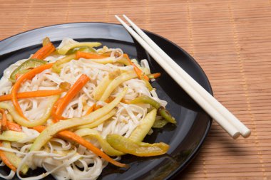 Sebzeli erişte ve bambu masa örtüsü üzerinde çubuk.