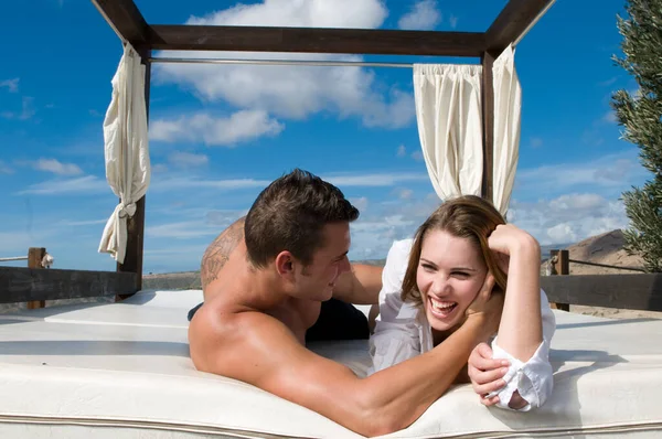 attractive young couple on chill out bed under blue summer sky