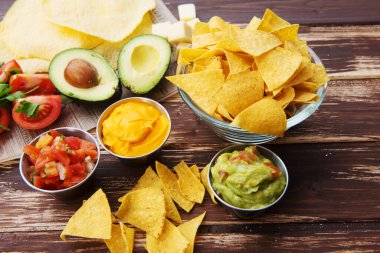Tahta masada guacamole soslu bir kase Meksika cipsi.