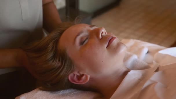 在豪华的温泉沙龙里躺着一个松懈的 闭着眼睛的女人来做按摩头的治疗 减轻压力和恢复活力的概念 — 图库视频影像