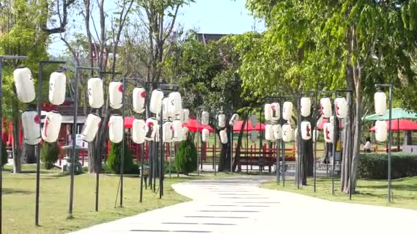 传统的日本纸制灯笼挂在主题公园的小径附近 日本的咽喉灯笼 上面有亚洲女人的美丽照片 日本文化 旅行和旅游概念 — 图库视频影像