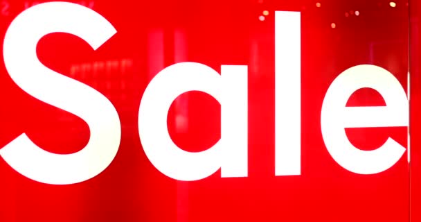 店内のガラスの入り口に白いSaleの言葉で赤い背景に大きな看板 ブラックフライデー中の近代的なショッピングモールでのプロモーション 季節割引を店舗で提供 — ストック動画