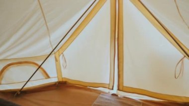 Dağda seyahat, modern konforlu kamp çadırının manzarası muhteşem yeşil tepelerde yataklı. Kanvas çadırından çıkıp güneşin doğuşunda kanyon manzarasının tadını çıkaran bir kadın..