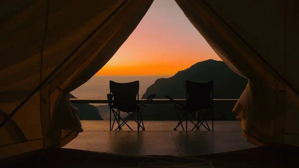 营地内的旅游帐篷 日出尽收眼底 尽收眼底 从夕阳西下的帐篷 高山和两张折叠式露营椅可以看到 自然旅行 流浪欲望 免版税图库照片