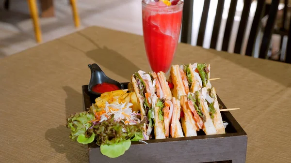 Four sandwiches on the board. Sandwich with ham, tomatoes, lettuce, toasted bread, served with french fries and bbq ketchup sauce. Club sandwich on a wooden table in cafe.