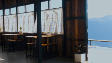 Sabahın köründe sisli dağlara bakan yerel bir kafe. Parlak gündoğumu ışığı pencerelerden süzülüyor, beyaz tülleri sallıyor, tahta masalarda ve kafede sandalyeler sallıyor. Doğa tatili kavramı.