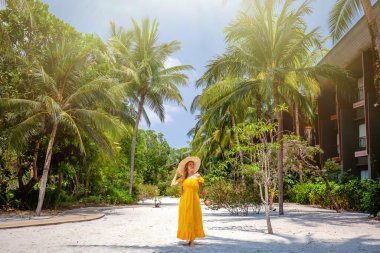 Seyahat eden kadın, tropik tatil beldesinde. Parlak sarı elbiseli ve hasır şapkalı mutlu genç bayan gezgin lüks Palm Beach tatil beldesinde yaz tatilinin tadını çıkar. Tayland 'a gezi