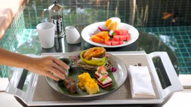 Tatlı pastalı tepsi, arka planda yüzme havuzu olan bir parça çikolatalı pasta. Pastane, kruvasan ve taze egzotik meyveler. Tatil köyünde nefis yemekler. Oda servisi.