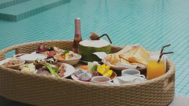 在游泳池里放着各种热带水果 果汁和椰子的早餐盘 芒果和葡萄片 泰国奢华的旅行 度假和放松 — 图库视频影像