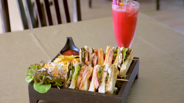 有火腿 西红柿和烤面包 绿色新鲜沙拉和西瓜的俱乐部三明治在咖啡店里摇匀 美国传统咖啡馆或餐馆里乡村木桌上的四个三明治 — 图库视频影像
