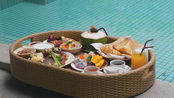 在豪华酒店里漂浮着早餐盘 酒店早餐 新鲜羊角面包 热带水果和果汁 豪华旅行 泰国度假 异国情调的夏季旅行 — 图库视频影像