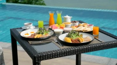 Tropical breakfast with fresh fruit by the swimming pool on terrace with turquoise sea view. Summer travel holiday. Fresh Breakfast in beautiful location with ocean views