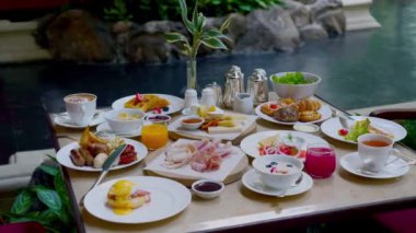 Table full of various fresh food in luxury modern restaurant in hotel. Delicious dishes, including fruits, pastries, cooked meals on table. Restaurant setting, modern decor, sophisticated atmosphere