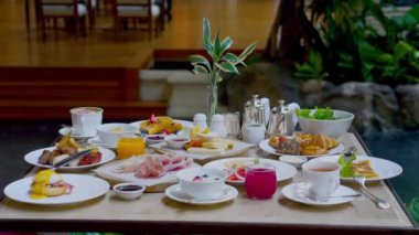 Table full of various fresh food in luxury modern restaurant in hotel. Delicious dishes, including fruits, pastries, and cooked meals on table. Restaurant setting. Breakfast or morning meal