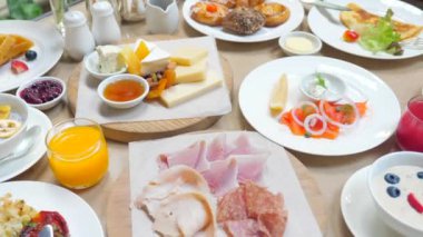 Table full of various fresh food in luxury modern restaurant. Delicious dishes, cold cuts, salmon, omelette, pastries, juices, cheese. Delicious and lavish breakfast or morning meal in high-end hotel