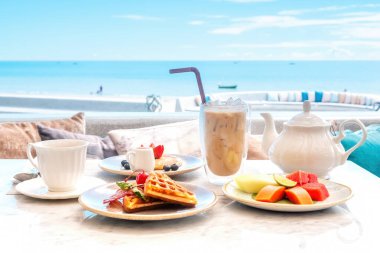 Beachfront hotel breakfast, beautiful morning on beach. Enjoy delicious meal with sea view. Relax and enjoy ocean and sound of waves. Beach, vacation, tropical holidays, travel.
