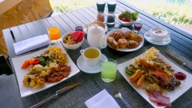Fresh breakfast at beautiful luxury summer vacation. Table is filled with gourmet food, perfect for a honeymoon or special getaway. Enjoy the idyllic surroundings near the sea and pool.