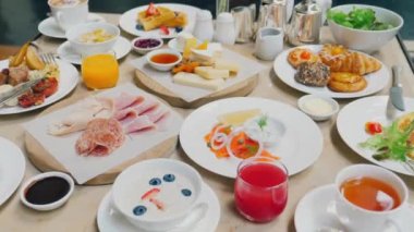 Hotel restaurant sets breakfast with coffee, orange juice and eggs. The buffet table brims with options - savory, sweet, pastries, hot and cold drinks.