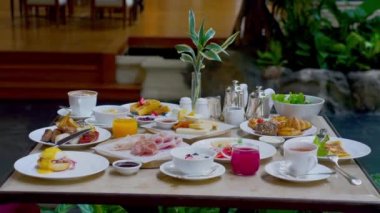 Hotel breakfast setting - coffee, fresh orange juice, eggs on table in luxury restaurant. Buffet table overflowing with an assortment of savory and sweet items, pastries, hot drinks and juices.