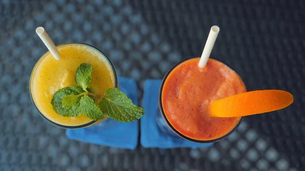 Top view of papaya and mango smoothie with paper straws on restaurant table, refreshing and healthy drink. Close-up of smoothie, detoxing and clean eating. Vibrant colors. Natural beverage.