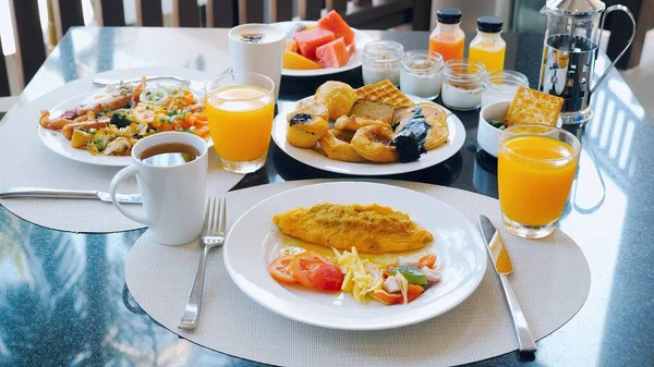 Luxury hotel breakfast buffet with a variety of food. Omelettes and fresh desserts, buns and croissants. Delicious plate of food on the dining table. Juice and coffee cups