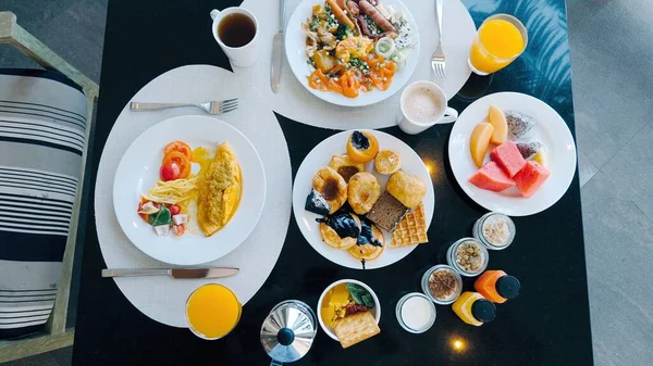 Hotel breakfast buffet with variety of food. Top view of tropical breakfast. Fresh pastries, eggs, fruits, juices, and coffee on table. Colorful spread with tropical fruits and tea.