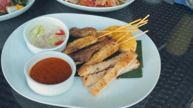 Grilled chicken skewers with bread, onions, and spicy sauce. Famous Southeast Asian dish. Tasty Thai Chicken Satay with Peanut Sauce. Barbecued skewers, summer cookout.