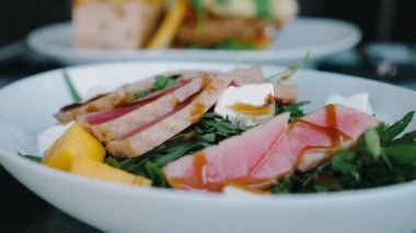 Taze ton balıklı sashimi salatasını meyve, peynir ve roka ile kapatın. Düşük karbonhidratlı diyetler için mükemmel. Restoran masasında servis edildi..