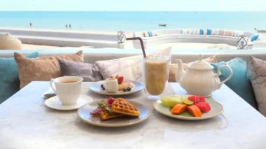 Beachfront hotel breakfast, beautiful morning on beach. Enjoy delicious meal with sea view. Relax and enjoy ocean and sound of waves. Beach, vacation, tropical holidays, travel.