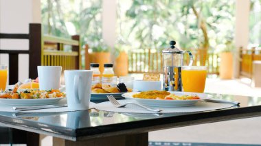 Tropical breakfast buffet at hotel. Fresh food and juices served in luxury outdoor restaurant with palm trees on background. Perfect vacation breakfast.