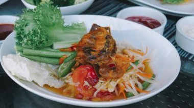 Som Tam, a traditional Thai green papaya salad served with fried crab, peanuts, green beans, and tomatoes. Delicious Asian food served at restaurant.